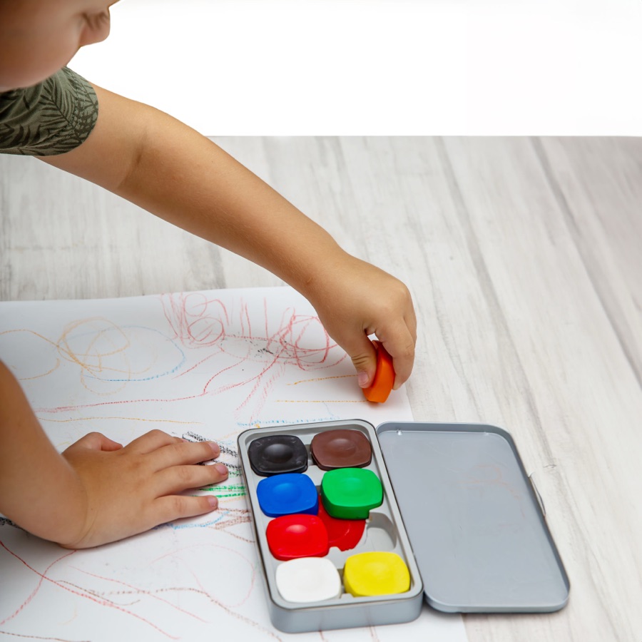 A child drawing with crayons at a table