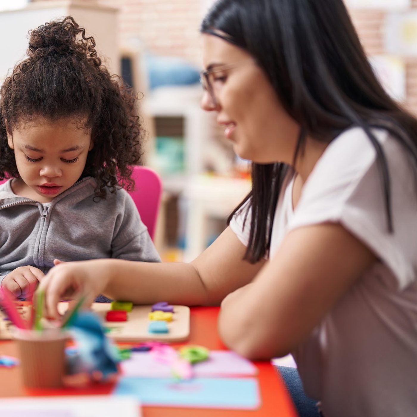 A therapist and toddler doing a puzzle together at a table